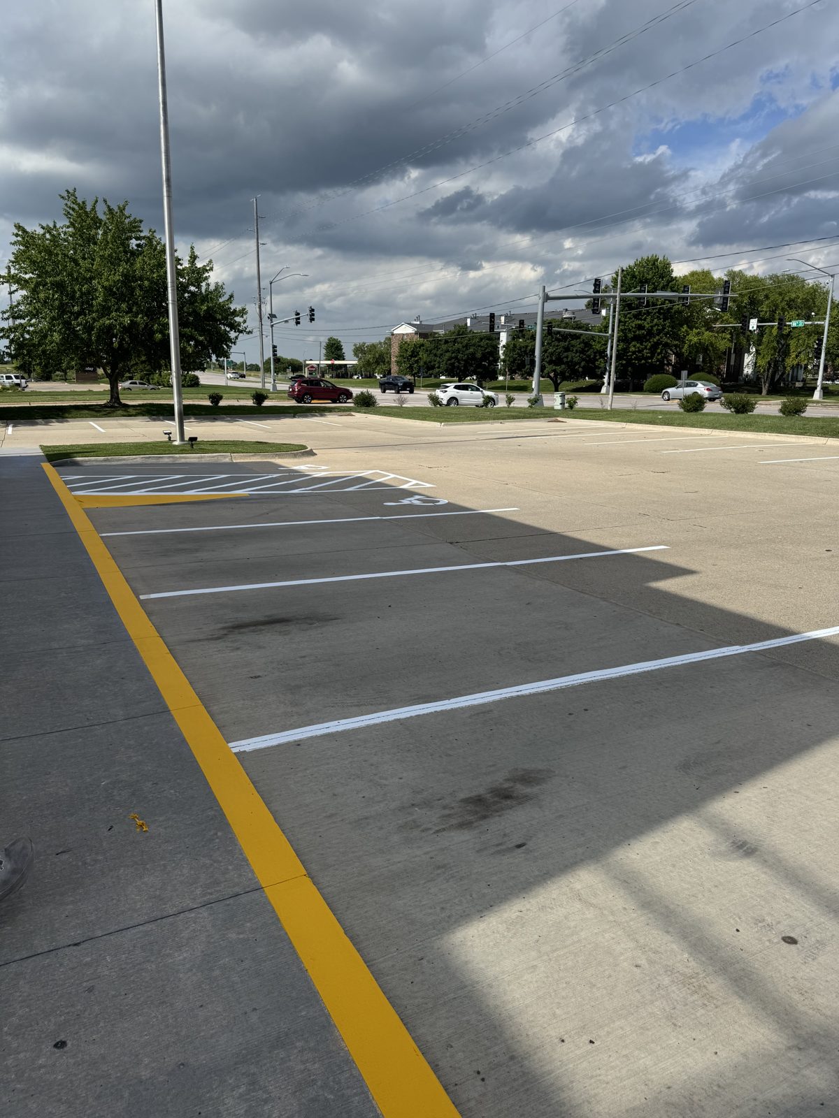 Freshly striped parking lot with bright white stalls and a new yellow curb in Des Moines, IA
