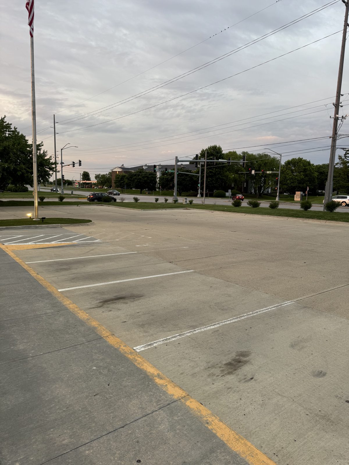Faded parking lot lines and worn yellow curb before striping in Des Moines, IA